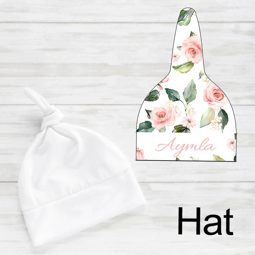 Baby hat with a knot, shown next to a design template featuring pink roses and green leaves. Text "Aymla" is written in pink script on the floral design.