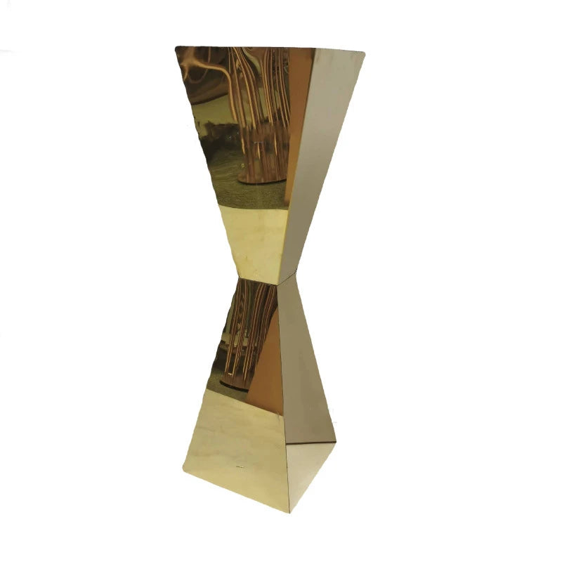Gold-toned, hourglass-shaped reflective sculpture with a twisted middle section, standing upright against a white background. The surface reflects its surroundings.
