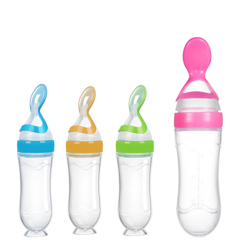 Four soft-tip baby feeding bottles with spoons, each with a colorful cap in blue, orange, green, and pink, arranged side by side on a white background.