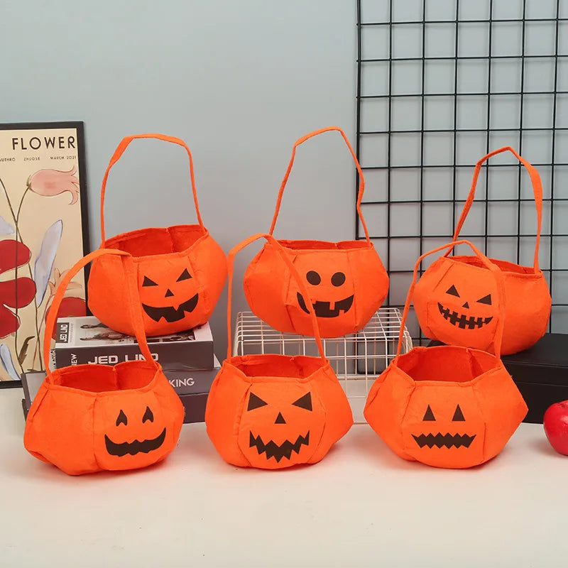 Six orange pumpkin-themed trick-or-treat bags with various smiling jack-o'-lantern faces, arranged in two rows on a table, with books and decor in the background.