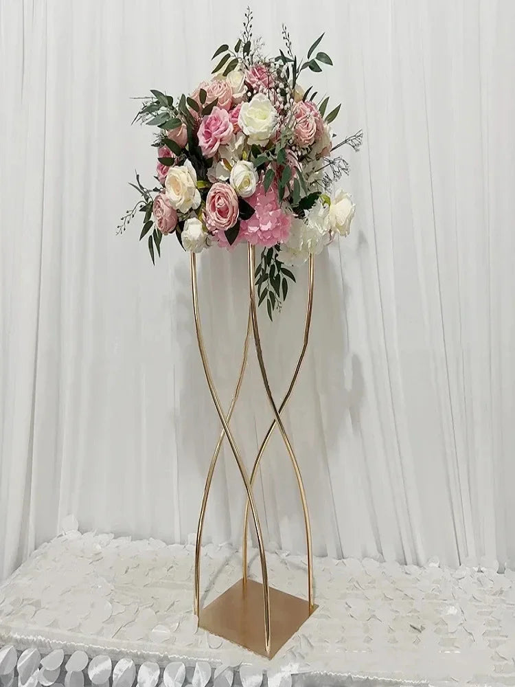 Elegant floral arrangement with pink and white roses, peonies, and greenery on a gold twisted stand. Displayed against a soft, white drape backdrop, resting on a textured tablecloth.