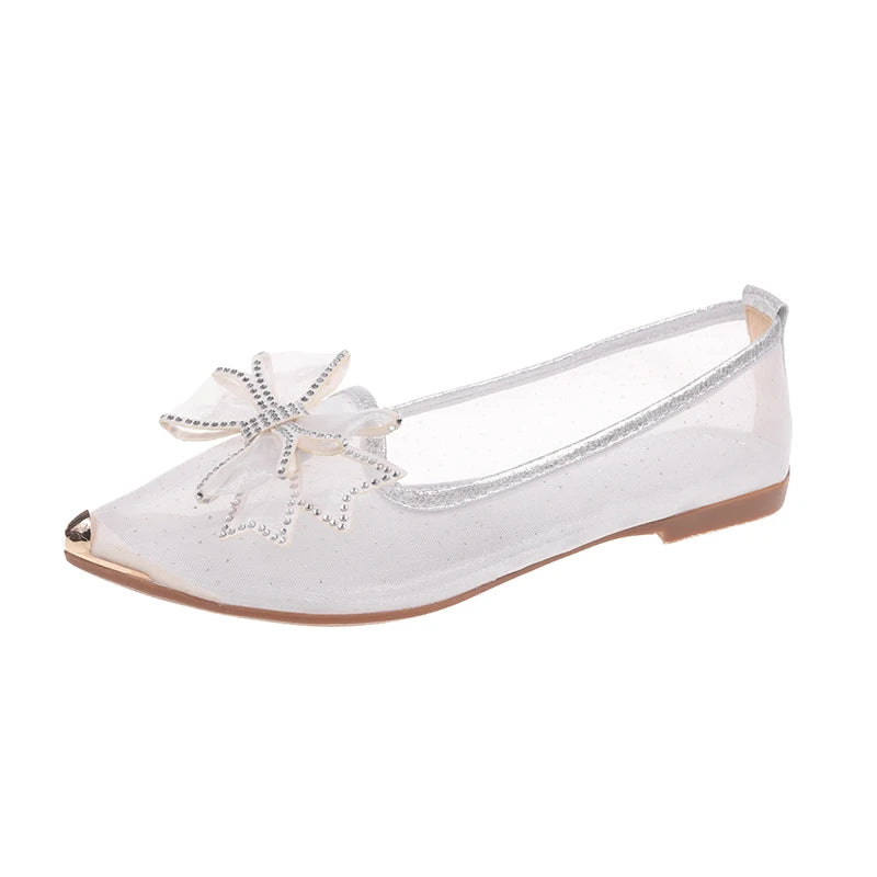 Transparent women's flat shoe with a pointed metallic toe, adorned with a rhinestone-studded bow on the upper. Features a sheer, lightweight design and a simple flat sole.