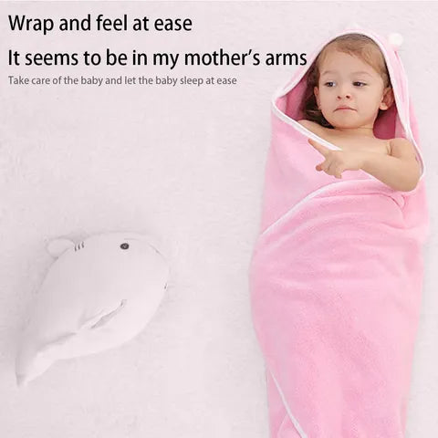 A toddler wrapped in a pink hooded towel lies on a white surface. Text above reads, "Wrap and feel at ease. It seems to be in my mother’s arms." A plush toy is beside the child.