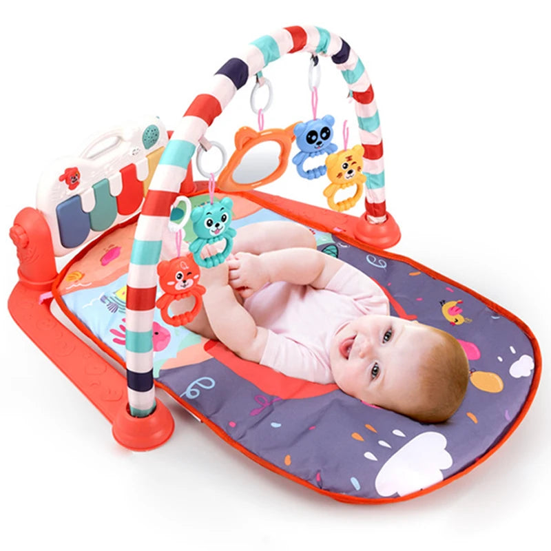 Baby lying on a colorful play mat with hanging animal toys and a striped arch. The baby is smiling, wearing a pink outfit. A small piano keyboard is attached to the mat.