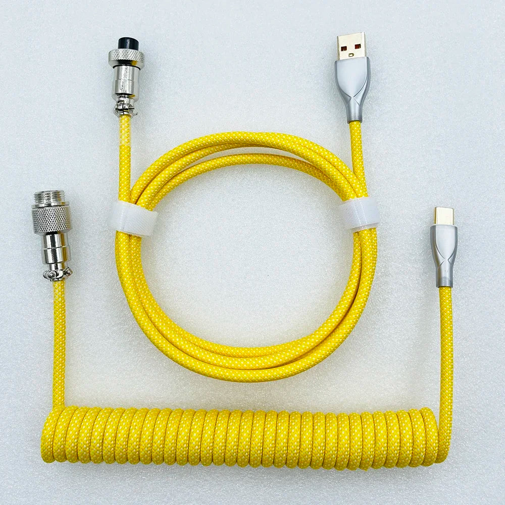 Yellow coiled USB cable with braided texture. It features USB-A and USB-C connectors and a sleek, silver finish, suited for durable and stylish connections.