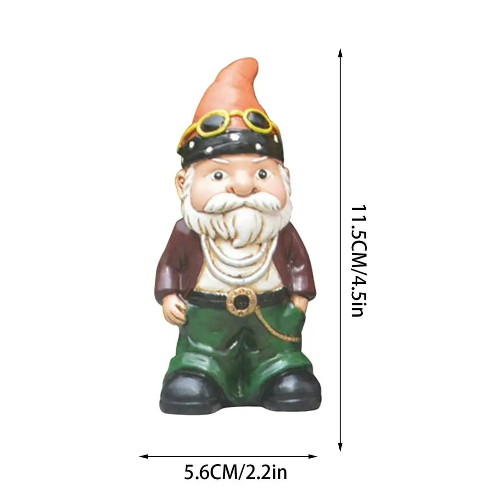 Garden gnome statue with goggles and an orange hat. It has a white beard, brown jacket, and green pants, standing 11.5cm tall and 5.6cm wide.