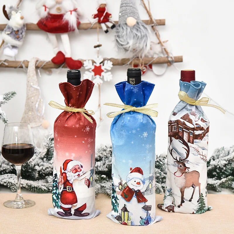 Three wine bottles are festively wrapped in Santa, snowman, and reindeer-themed covers. A glass of red wine sits nearby, with holiday decorations in the background.