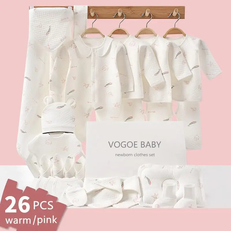 A 26-piece newborn clothes set in white with soft pink and feather patterns, displayed on hangers. Includes garments, a hat, and accessories with a "Vogoe Baby" label.