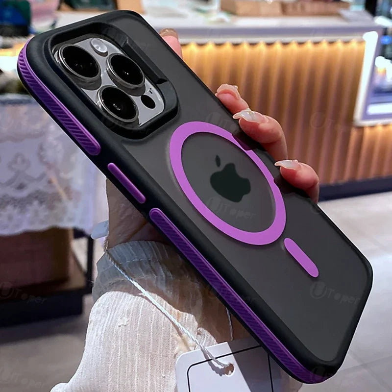 A hand holds an iPhone with a black and purple case showcasing a circular design on the back, highlighting the Apple logo. The background features a dimly lit interior setting.
