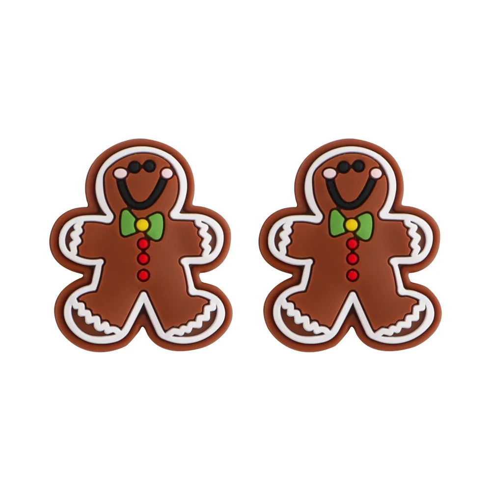 Two smiling gingerbread man cookies with brown icing, outlined in white, each wearing a green bow tie and red buttons, against a plain white background.