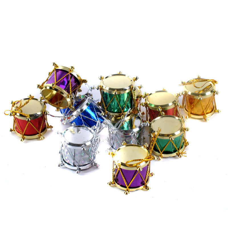 A collection of colorful miniature toy drums in red, blue, green, silver, and gold, with decorative gold and silver strings are scattered on a white background.