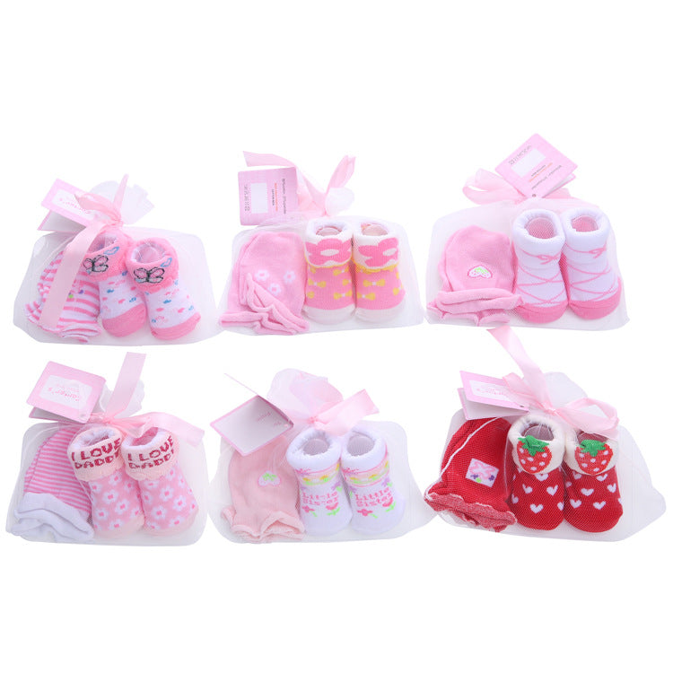 Six sets of baby socks in pink and red with cute patterns, bows, and heart motifs. Each set is packaged with a card and ribbon, arranged neatly in two rows.