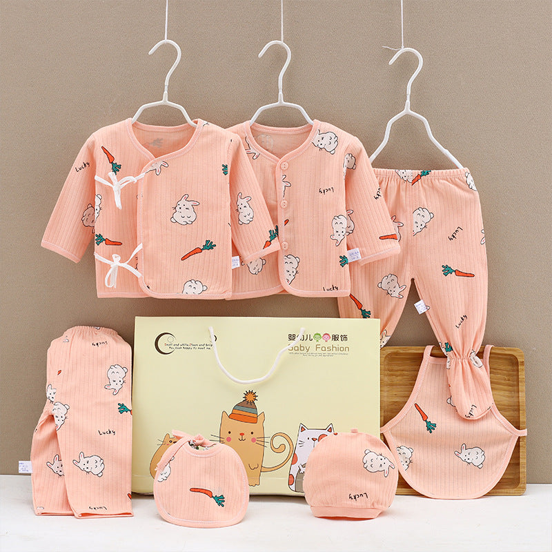 Set of peach-colored baby clothes with cute bunny and carrot designs, including shirts, pants, hat, and bib, displayed on hangers with a matching gift bag.