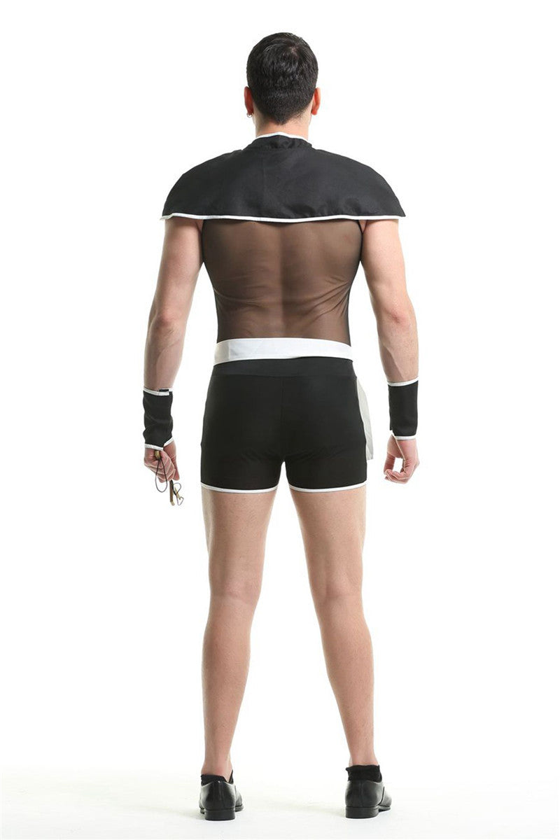 Man in a sheer top with a cape, black shorts with white trim, and black shoes, seen from behind. Holds a small accessory and wears wristbands. White backdrop.