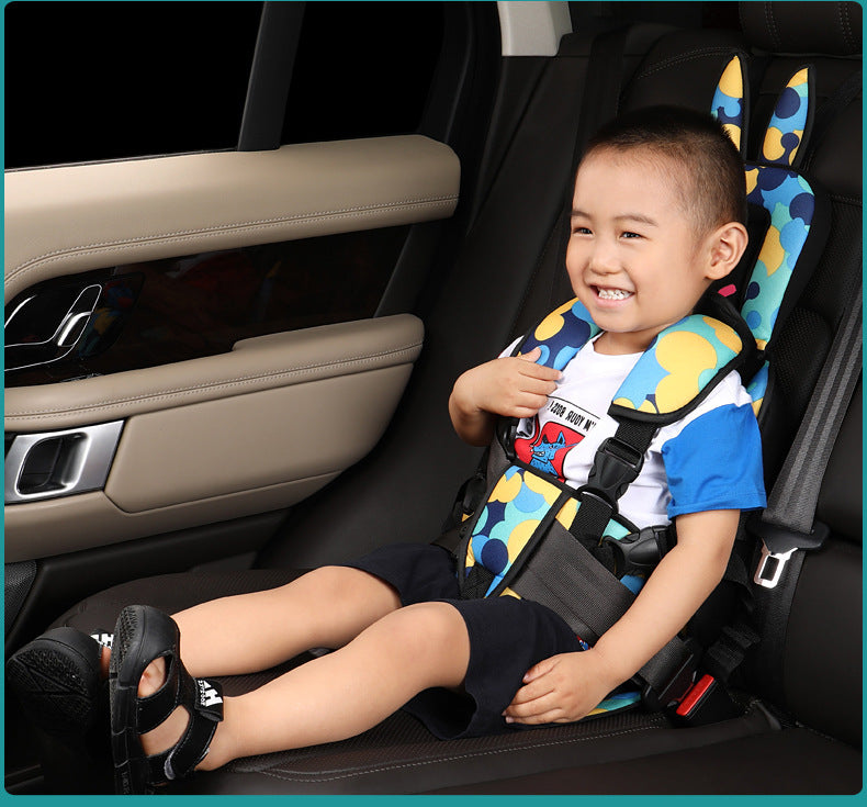 A smiling child sits securely in a car seat with colorful padding, featuring a playful pattern. The car's interior shows beige door panels and a sleek design.