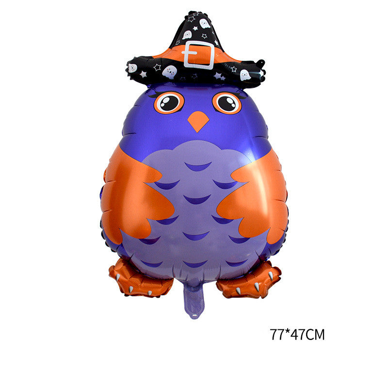 A purple and orange owl-shaped foil balloon with large eyes and wings is wearing a black witch hat decorated with white ghost and star patterns. The balloon size is indicated as 77 by 47 centimeters.