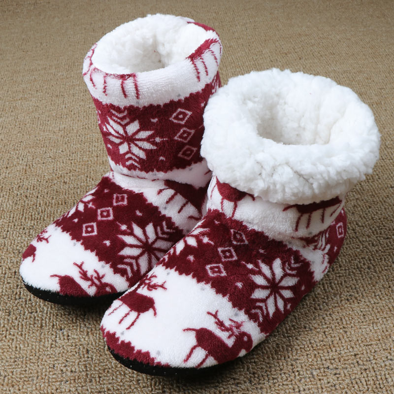 Cozy red and white knitted slippers with reindeer and snowflake patterns, featuring soft, fluffy interiors, resting on a textured beige carpet.