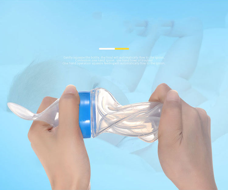 Hands holding a squeezable baby food dispenser with a spoon attached, against a blue background. The bottle is clear with a blue cap, and text is faintly visible.