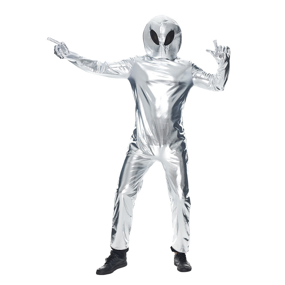 Person dressed in a shiny metallic silver alien costume, complete with a helmet featuring large black eyes. The suit covers from head to toe, and the person stands with arms outstretched. They wear black shoes and pose against a plain white background, creating a futuristic look.