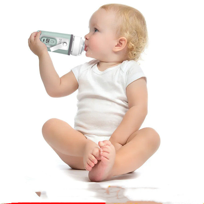 Baby in a white onesie sitting on the floor, drinking from a gray and white bottle with a digital display, against a plain white background.
