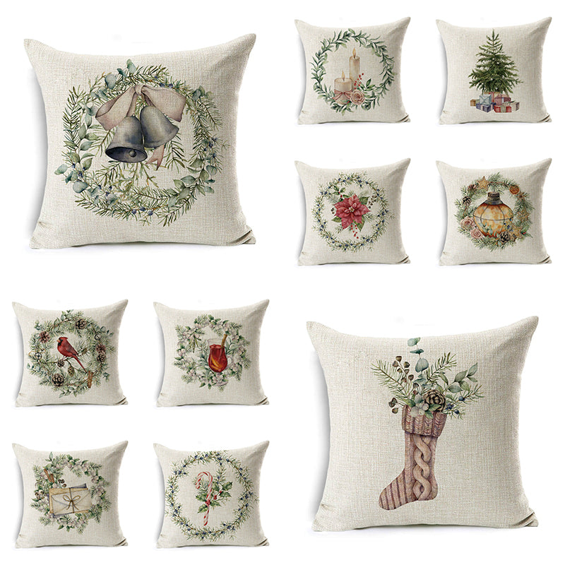 Collection of nine festive pillows featuring holiday motifs: bells, candles, tree, cardinal, ornament, poinsettia, gift, candy cane, and a stocking with greenery.