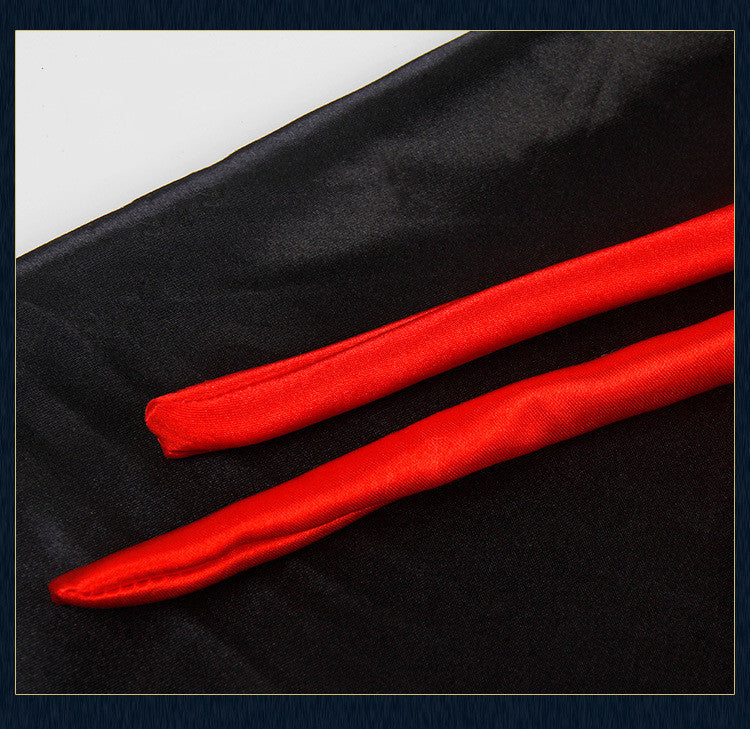 Two red satin sash belts lie parallel on a smooth black fabric background, displaying a striking contrast between the vibrant red and the deep black.