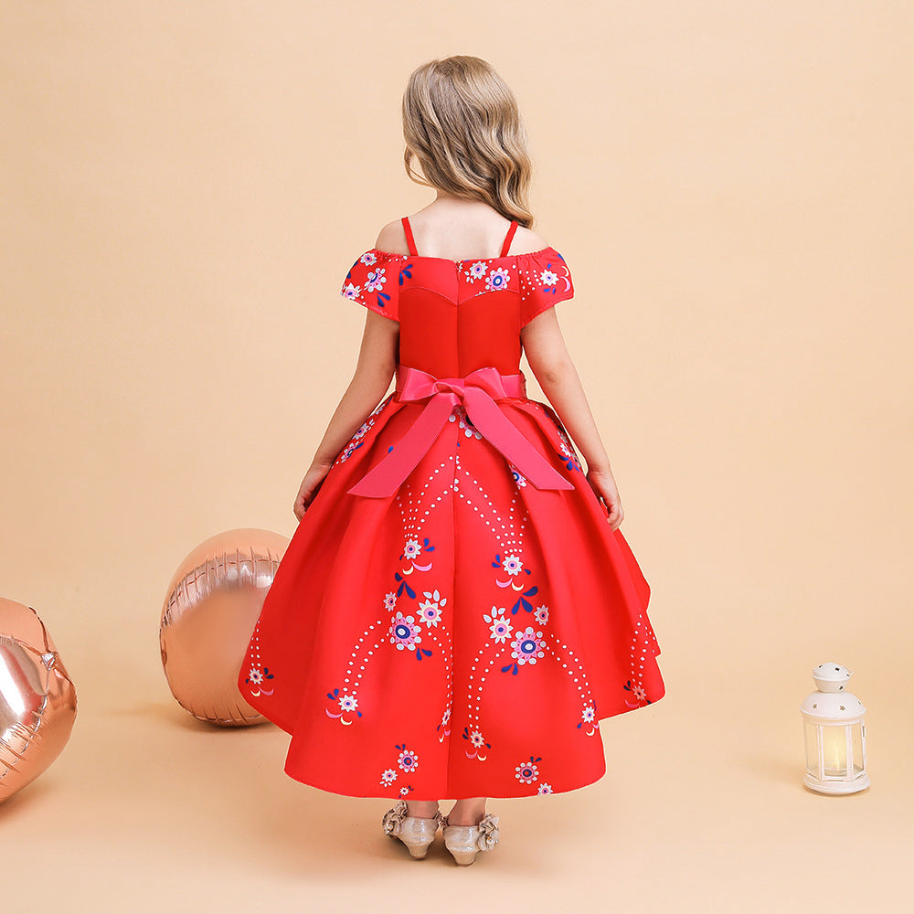Girl in red floral dress with pink bow stands against a beige backdrop. She is surrounded by rose-gold balloons and a white lantern. Dress has colorful floral patterns.