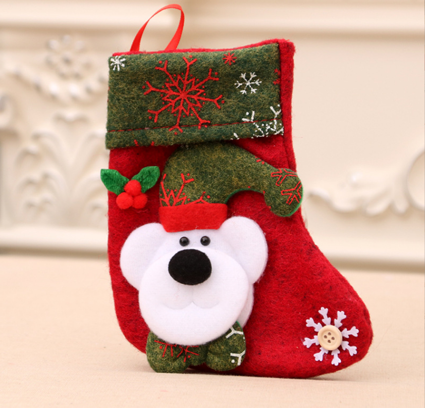 Red Christmas stocking with green trim, snowflake patterns, and a white bear face decoration. It features a felt holly accent and a snowflake button detail.