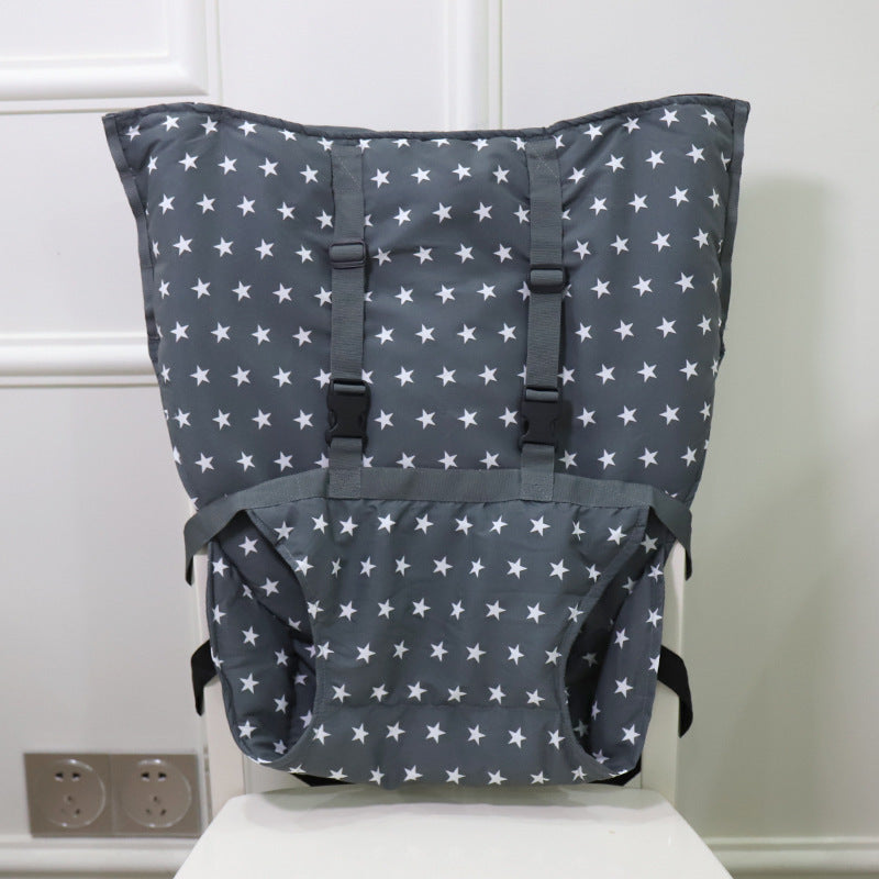 Gray cushioned mat with white stars, featuring adjustable straps, displayed against a white wall, and resting on a white surface near electrical outlets.