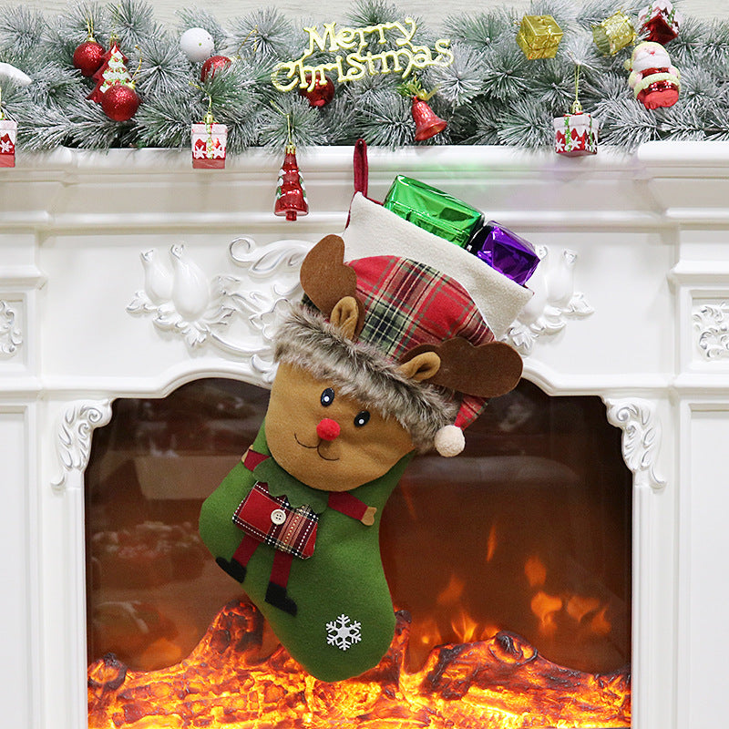 Christmas stocking with a reindeer design hangs from a white mantel decorated with ornaments and greenery. A "Merry Christmas" sign is above, and gifts peek out from the stocking.