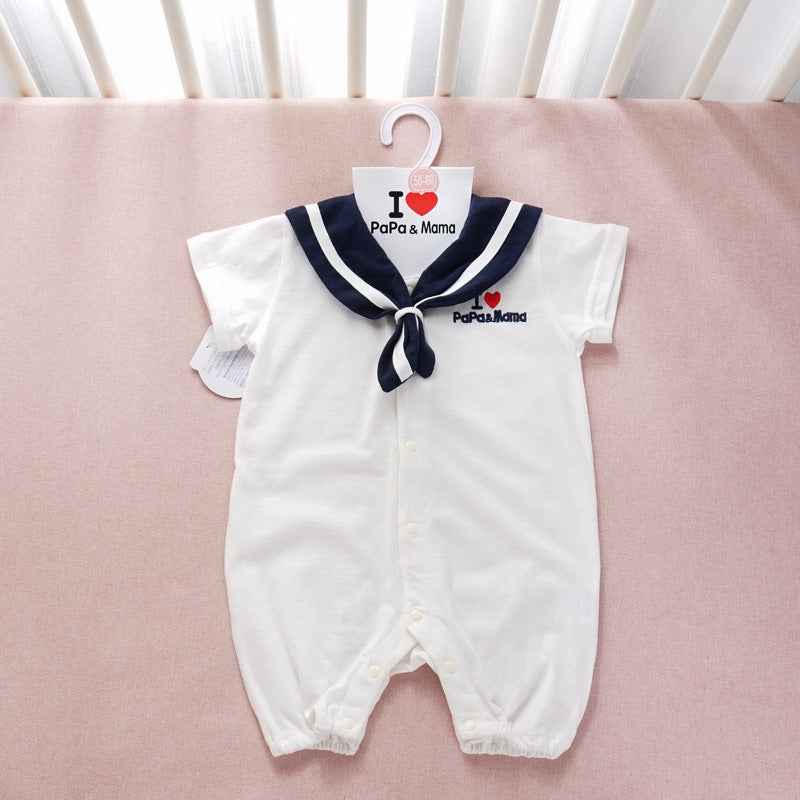 White baby romper styled as sailor suit with navy collar, featuring "I ♥ PaPa & Mama" text. It hangs on a hanger against a soft pink background.