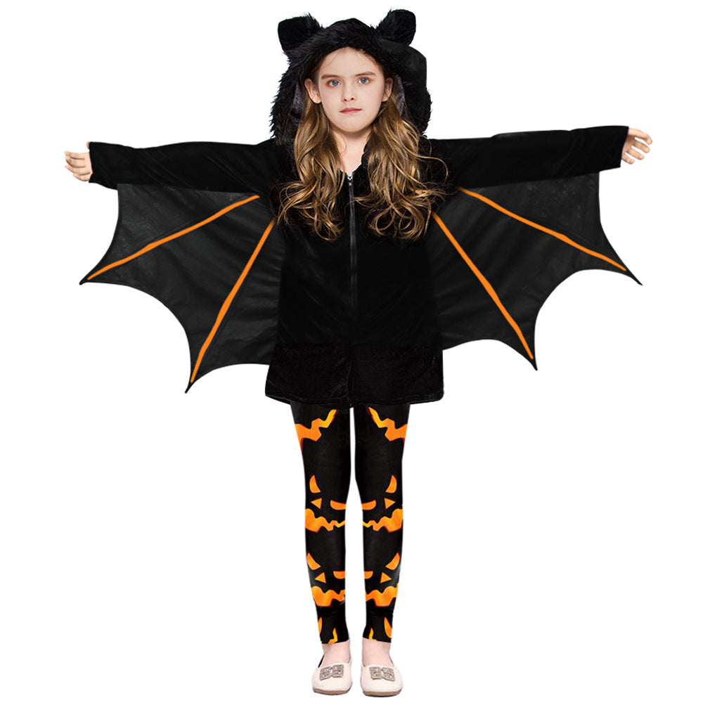 Child in a black bat costume with orange-trimmed wings, wearing Halloween-themed leggings with orange jack-o'-lantern faces, and a hood with ears.