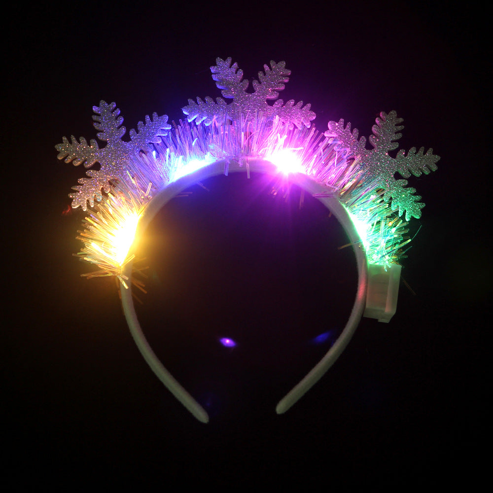 A glowing headband featuring iridescent snowflakes and multicolored LED lights against a dark background. The lights create a vibrant, festive look.