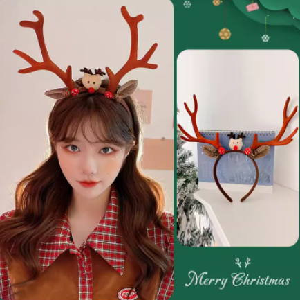 A person wearing a reindeer antler headband with a cute reindeer face and red baubles. The background has a Christmas theme with a "Merry Christmas" message.