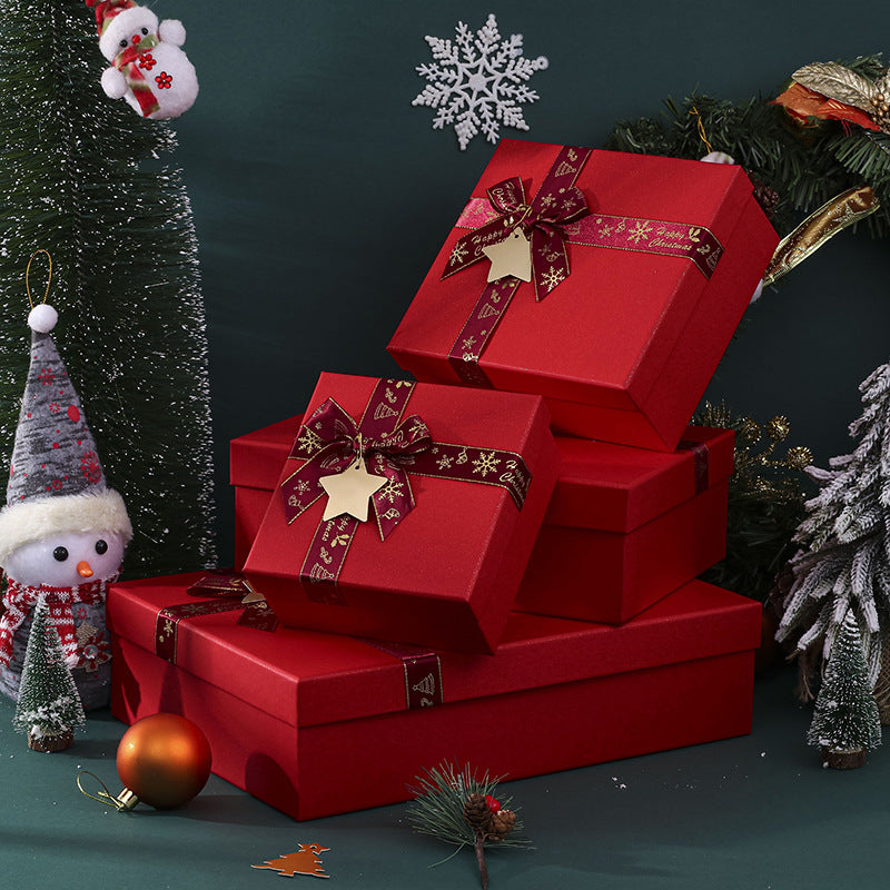 Red gift boxes adorned with ribbons and star tags surrounded by festive decorations, including a snowman figurine, ornaments, and small festive trees.