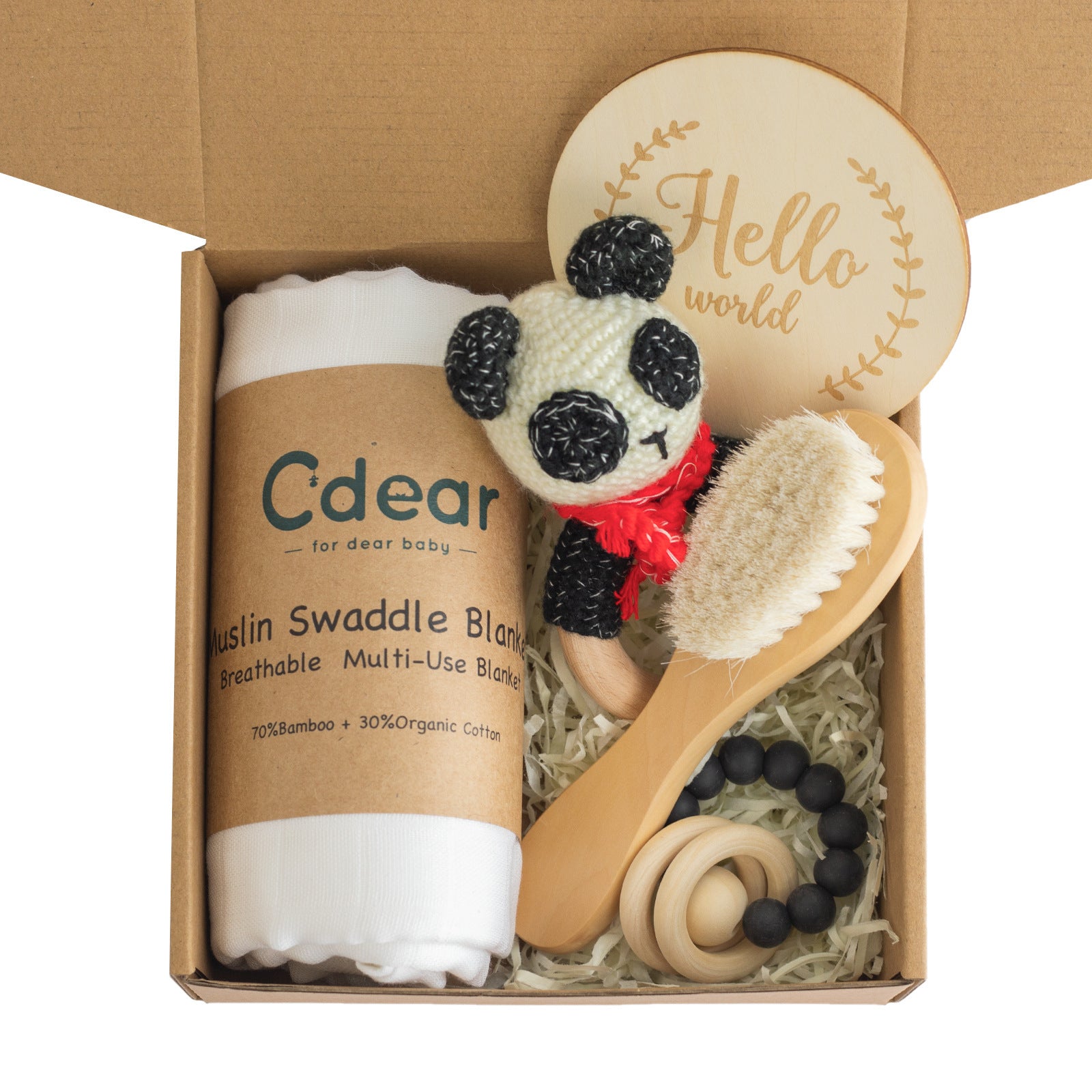 Gift box with a muslin swaddle blanket, crocheted panda toy, wooden baby brush, teething ring, and "Hello world" card, nestled in paper filling.