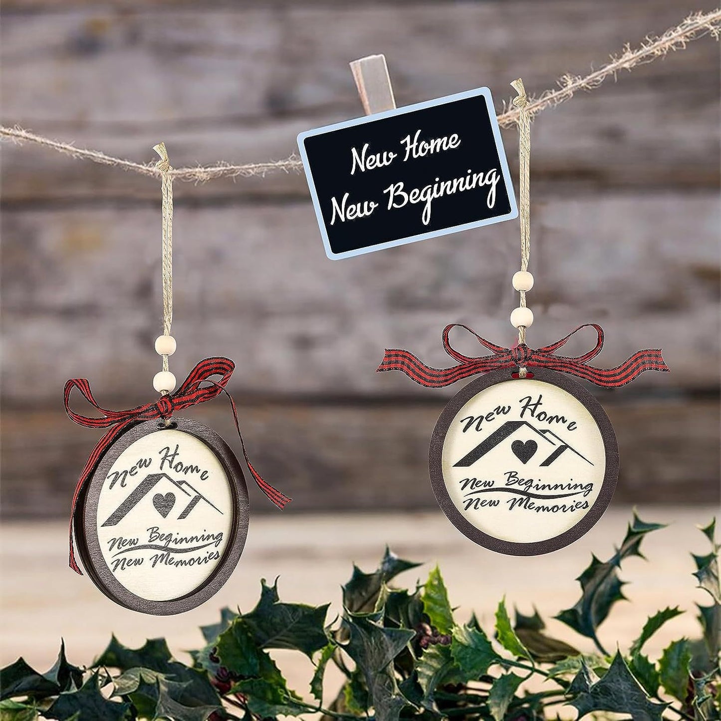 Two ornaments with red bows hang from a twine, each inscribed with "New Home, New Beginning, New Memories." A small sign above reads "New Home, New Beginning." Holly in the foreground.