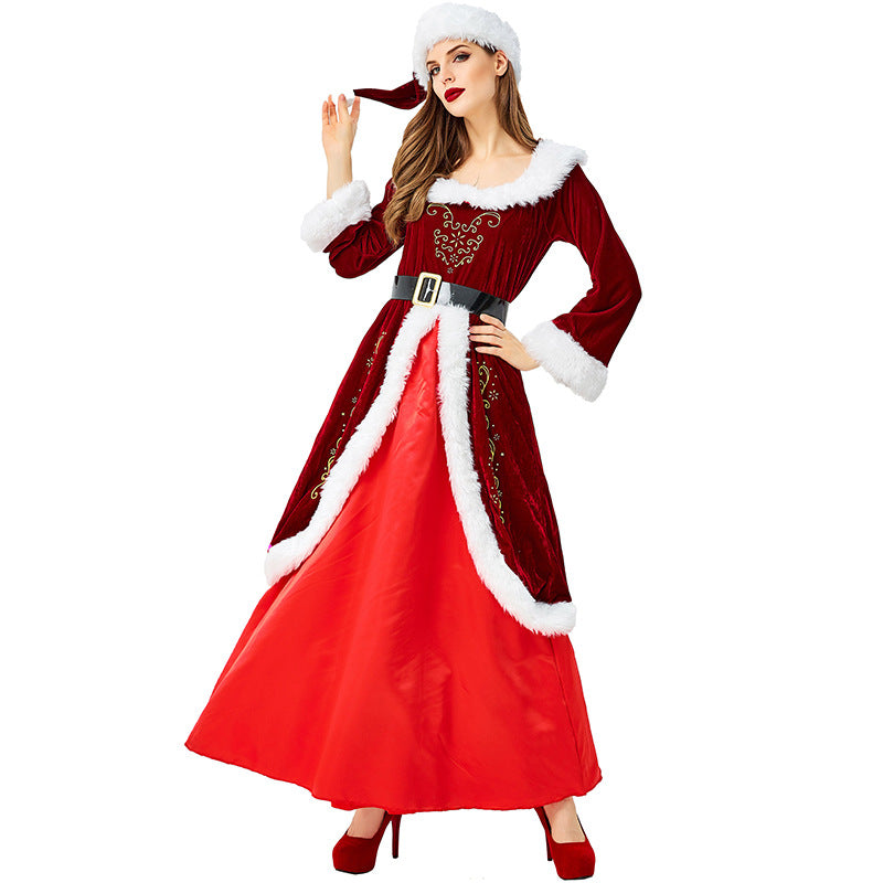 Woman in a festive red and white Santa-style dress with fur trim, wearing matching heels and a Santa hat, posing with a hand on her hip.