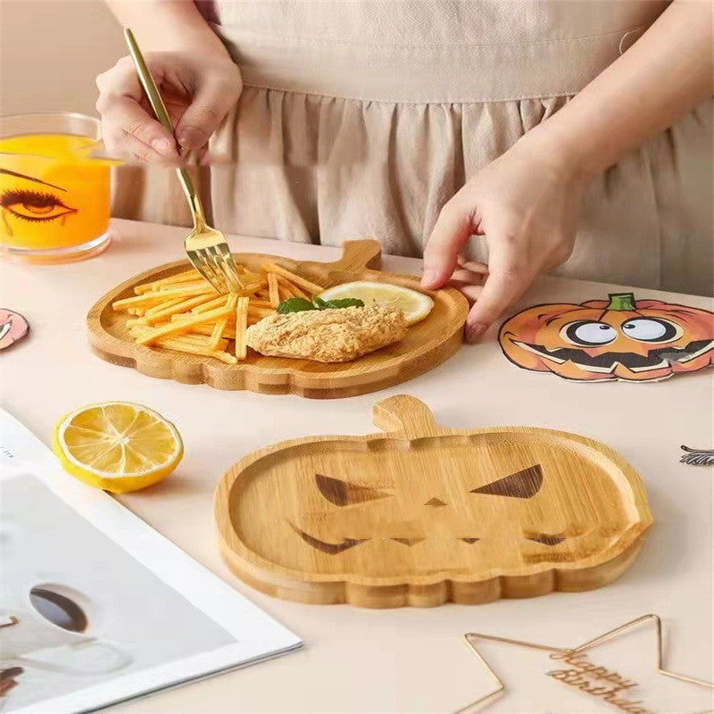 A person eating fries and a breaded cutlet from a pumpkin-shaped wooden plate. A lemon slice and orange drink sit nearby on a table with playful pumpkin-themed decor.
