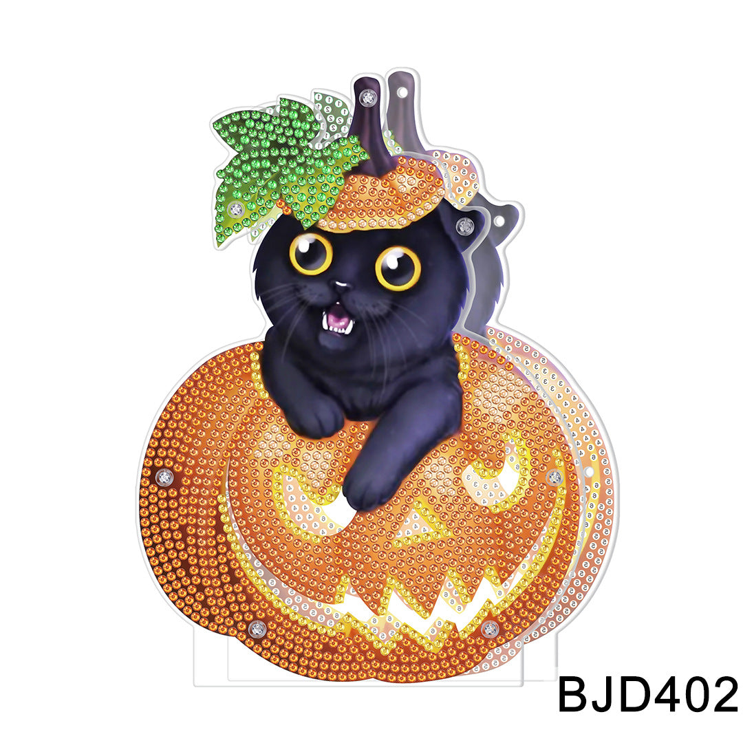 Black cat with yellow eyes peeks out of a sparkling jeweled pumpkin, wearing a small leaf hat. The pumpkin has a jack-o'-lantern face, with the code BJD402 visible.