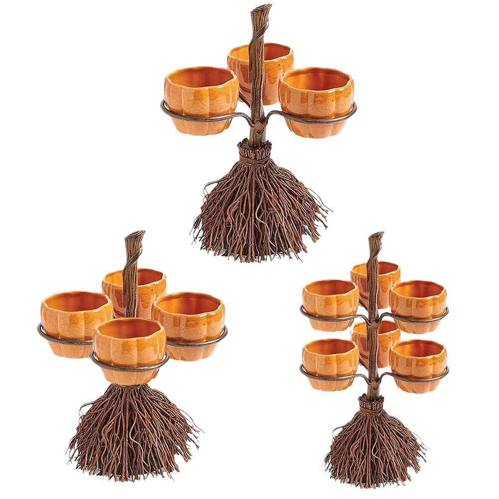 Three broomstick-shaped candle holders with orange pumpkin-shaped cups, each holding five cups arranged around the broomstick handle. The base resembles twigs.