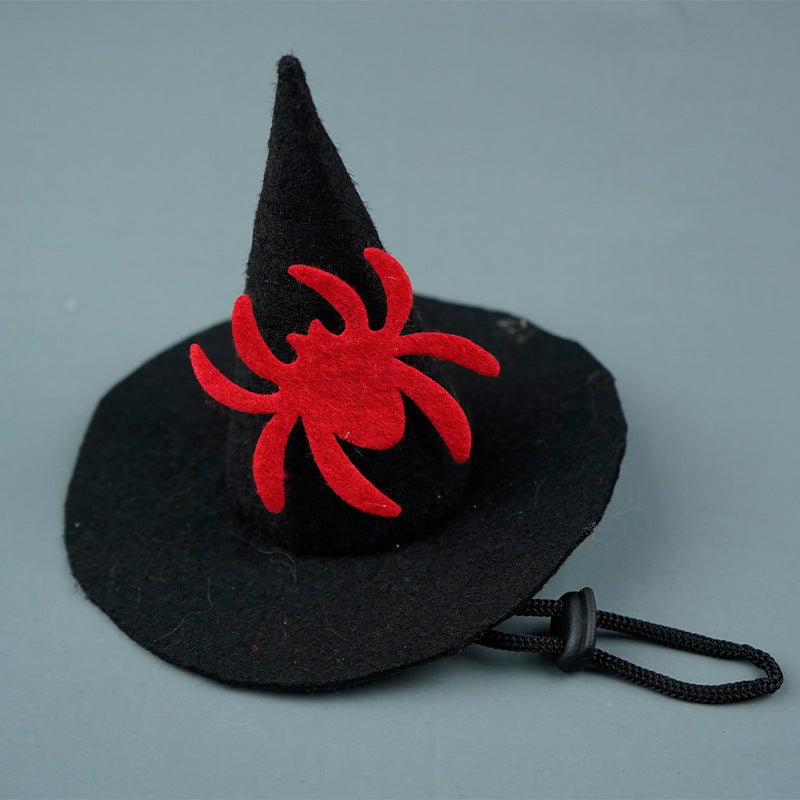 A small black witch hat with a bright red spider decoration on the front. The hat features an adjustable black elastic string for securing.
