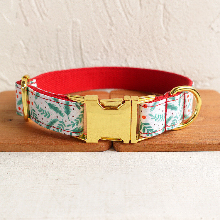 Festive dog collar with a red interior, floral holly pattern, and a shiny gold buckle, placed on a wooden surface.