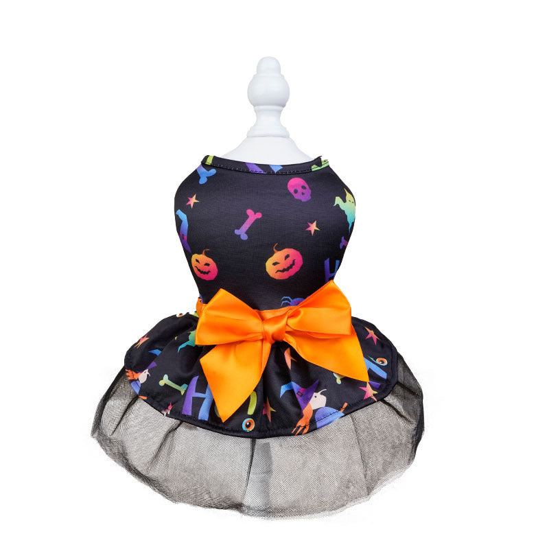 Dog dress with colorful Halloween-themed prints, featuring pumpkins and skulls. It has an orange bow at the waist and a black mesh skirt on a white display stand.