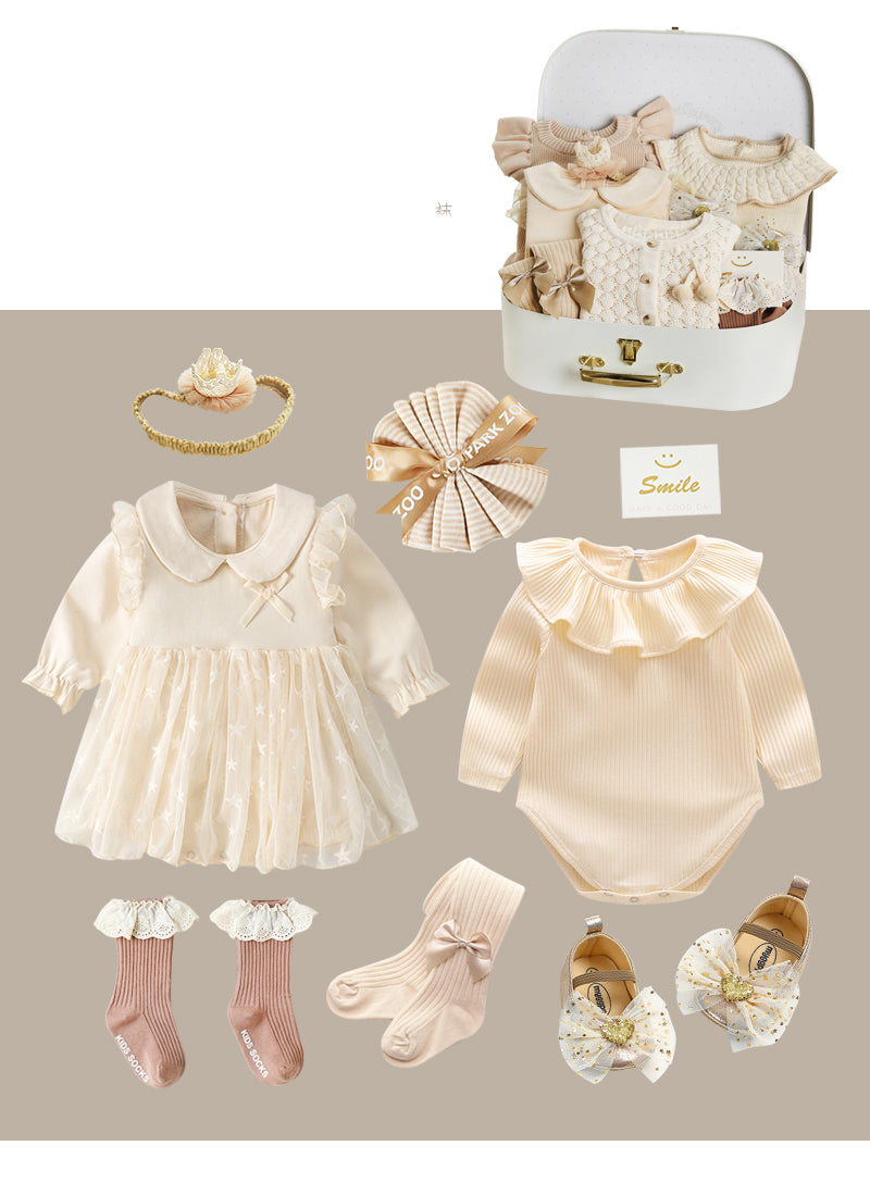 Cream baby clothing set includes a frilly dress, bodysuit, socks, shoes with bows, headband, and gift-wrapped items, along with a suitcase containing more clothes.