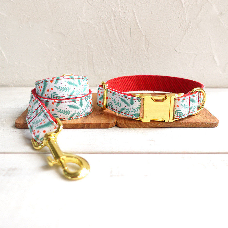 A dog leash and collar set with a festive design featuring red, green, and gold accents, displayed on wooden boards against a textured white background.