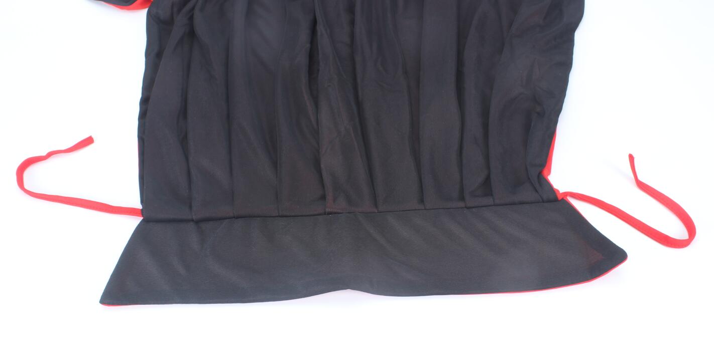 Black dress with red trim and waist ties, laid flat. The dress features pleated detailing and a wide hem.