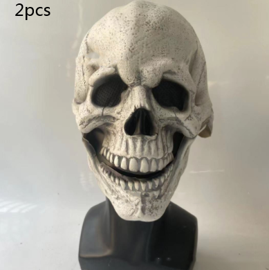 A white skull mask with detailed features, hollow eyes, and a wide grin sits on a black stand. Text in the top left corner reads "2pcs" against a plain background.