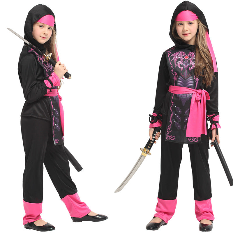 Two children wear black and pink ninja costumes, holding swords. The costumes feature intricate pink patterns and sashes, with matching headbands and shoes.