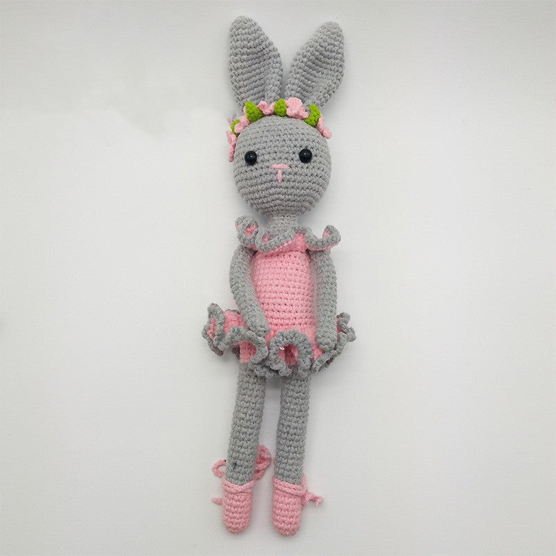 Cute grey crocheted rabbit wearing a pink dress, floral crown, and ballet shoes, set against a plain white background.